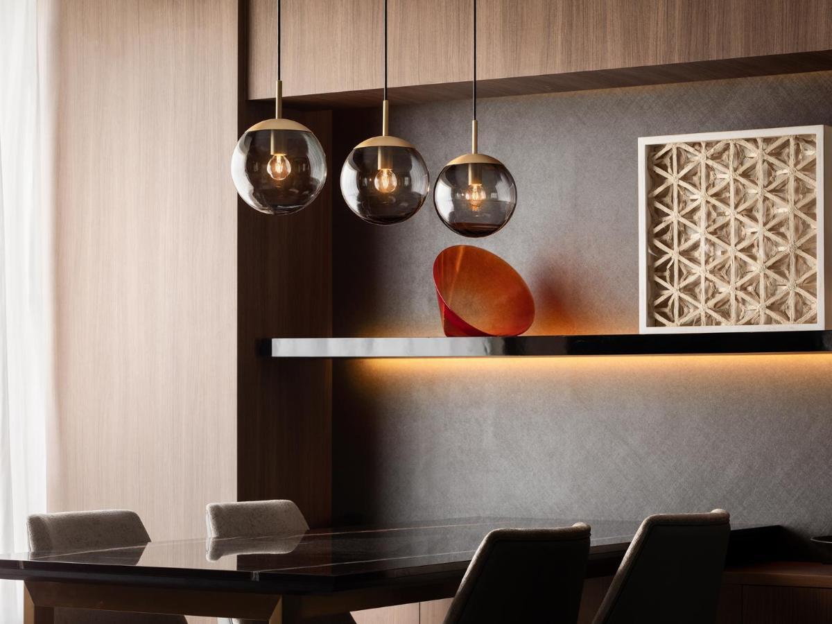 Mitsui Garden Hotel Roppongi Tokyo Premier Екстер'єр фото The photo depicts a modern interior design scene. It features a sleek dining area with a dark wooden table and comfortable chairs. Above the table, there are three pendant lights with glass shades that provide ambient lighting. A geometric art piece 