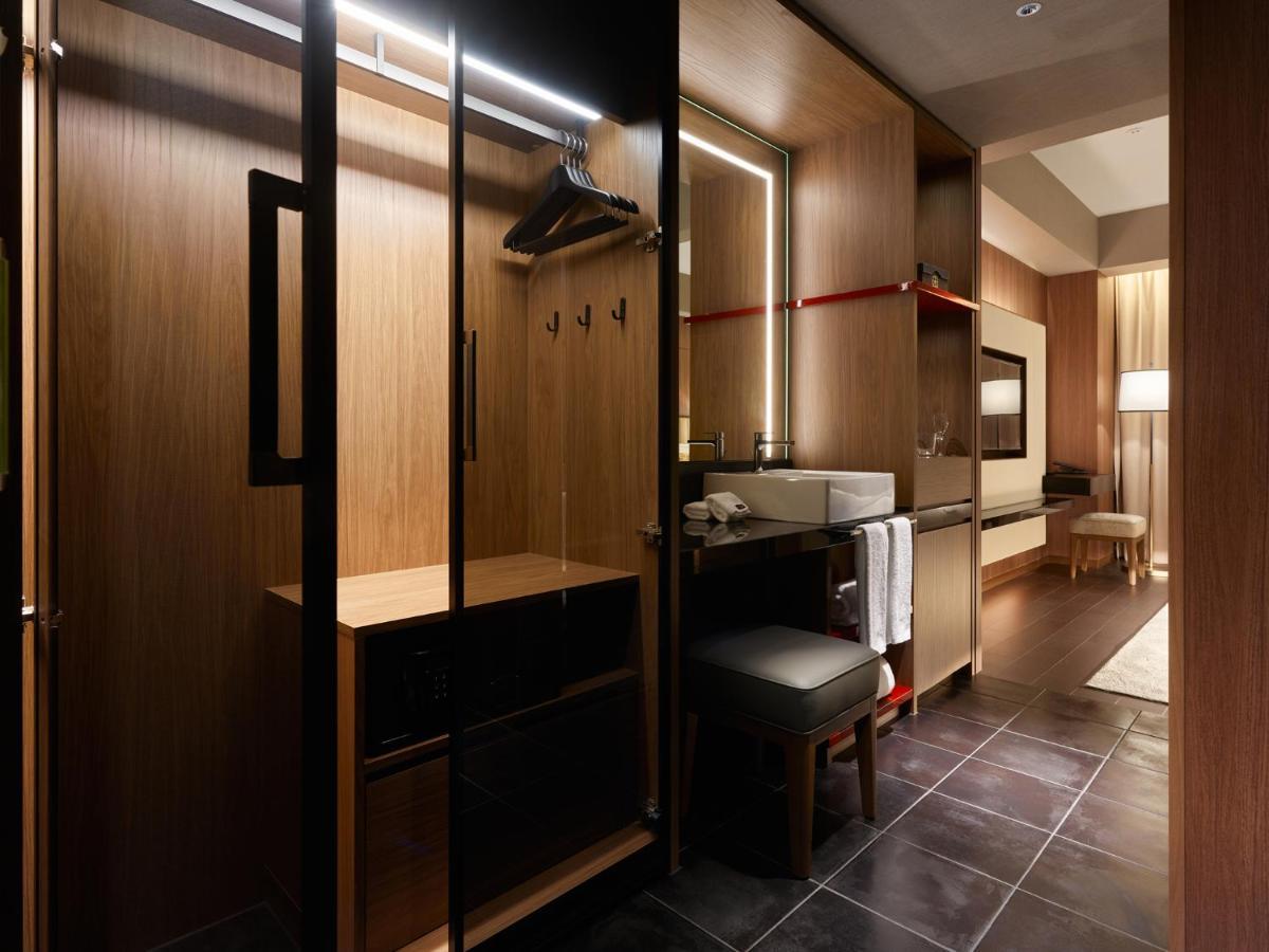 Mitsui Garden Hotel Roppongi Tokyo Premier Екстер'єр фото The photo depicts a modern and stylish hotel room's closet area. It features wooden cabinetry with a sleek finish, including mirrored doors. Inside, there are hangers for clothing and hooks mounted on the wall. A small bench or chair is positioned ne