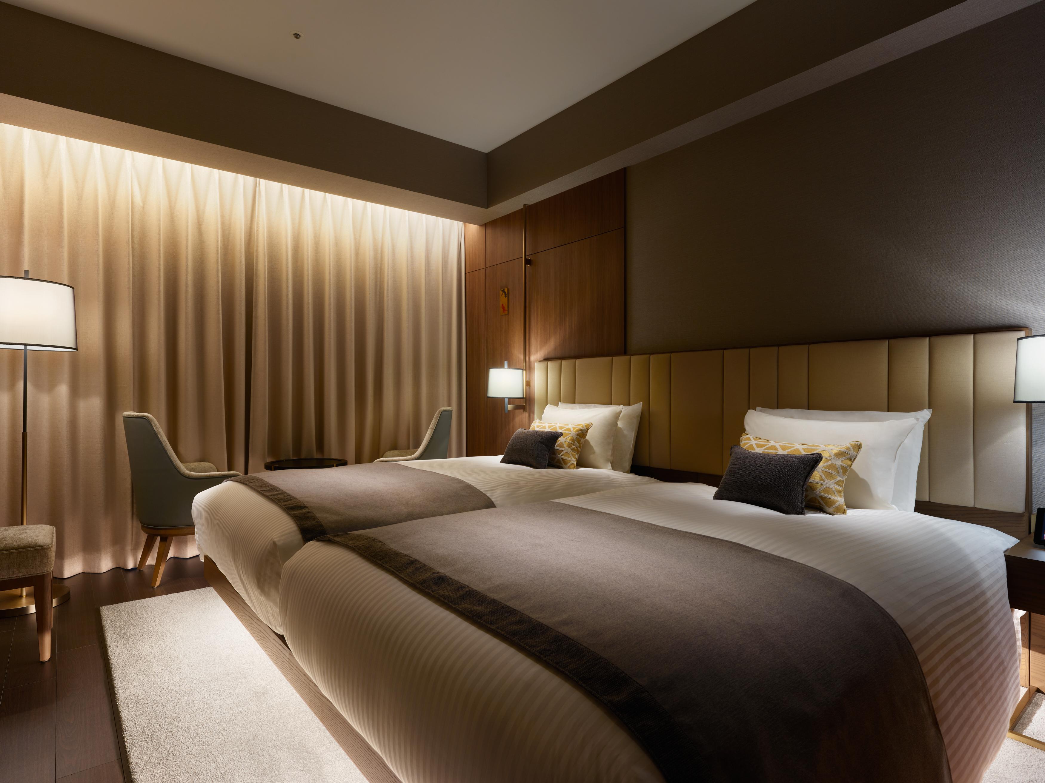 Mitsui Garden Hotel Roppongi Tokyo Premier Екстер'єр фото The photo shows a modern hotel room featuring two twin beds with elegant bedding. The room is adorned with soft, neutral tones and has a warm ambiance created by subtle lighting. A pair of bedside lamps provide additional light, and there is a cozy c
