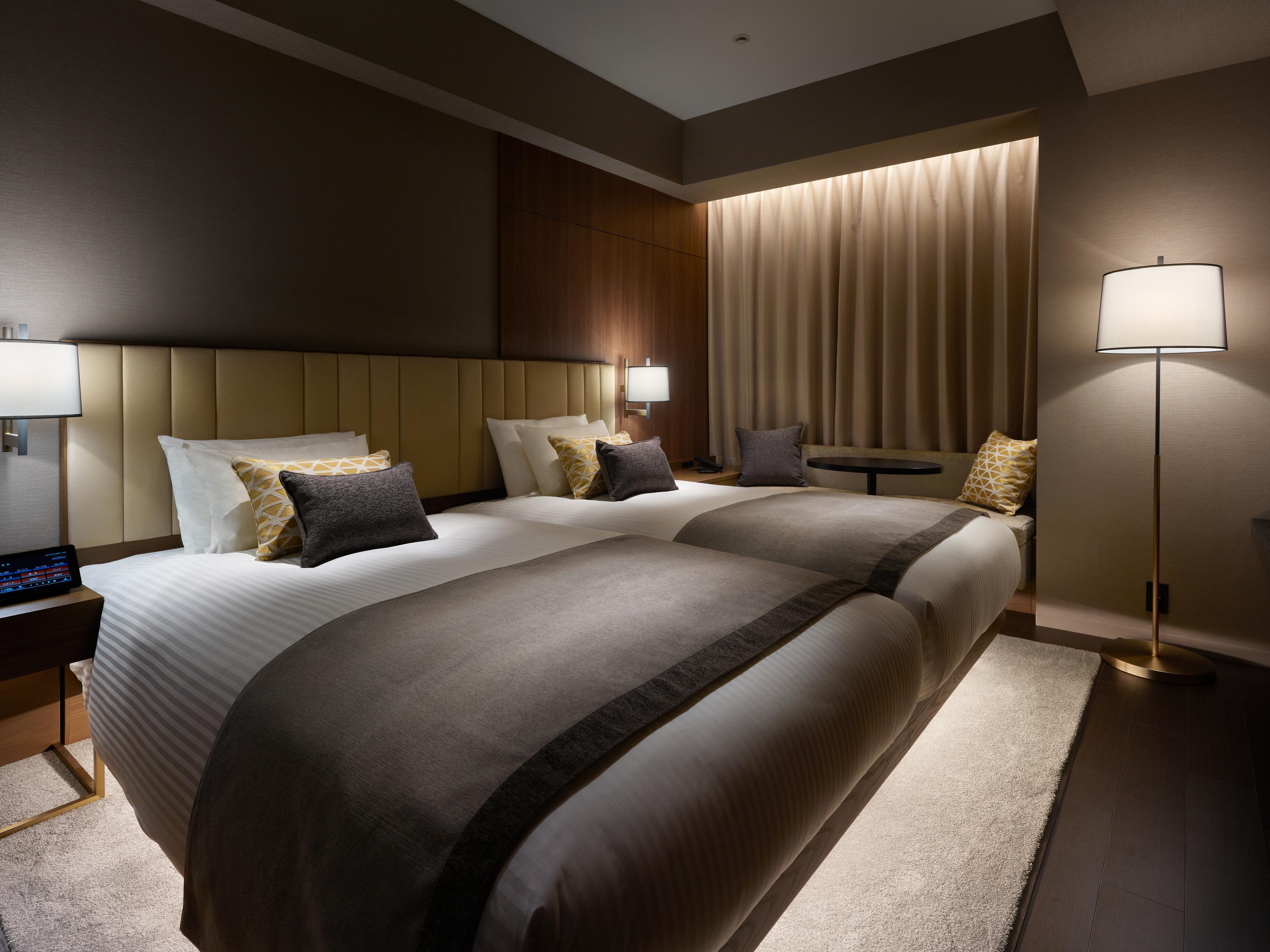 Mitsui Garden Hotel Roppongi Tokyo Premier Екстер'єр фото The photo shows a modern hotel room featuring two beds with elegant bedding in neutral colors. Each bed is adorned with decorative pillows. The room has a sophisticated ambiance with dim lighting, highlighted by table lamps on either side of the beds