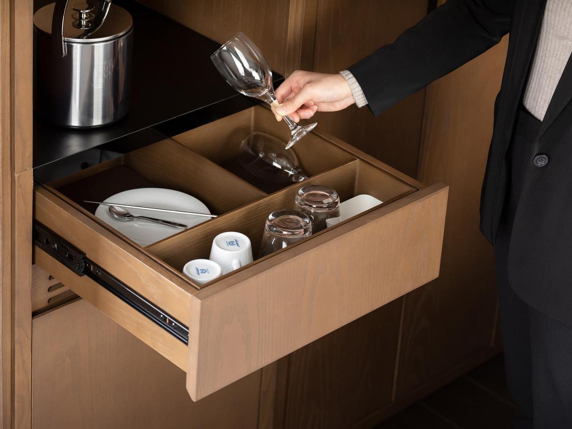 Mitsui Garden Hotel Roppongi Tokyo Premier Екстер'єр фото The photo depicts a wooden kitchen drawer being pulled open, revealing a neatly organized selection of dishware. Inside, there are glass cups, a wine glass being held by a person, and plates. The setting appears modern and sleek, with a sophisticated